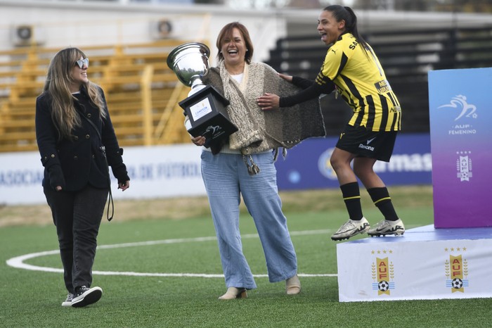 Wendy Carballo, de Peñarol, recibe el trofeo de de campeonas de manos de Mariana Fernández, presidenta de AUF Femenino. · Foto: Sandro Pereyra