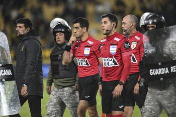 La terna arbitral sale escoltada por la guardia republicana tras suspender el partido. · Foto: Guillermo Legaria