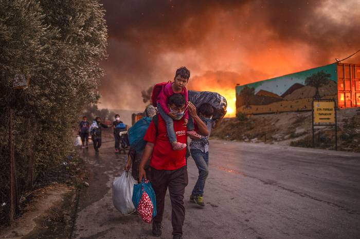 Personas huyen después de que estallara un gran incendio, ayer, en el campamento de migrantes de Moria en la isla griega de Lesbos, en el mar Egeo.  · Foto: Angelos Tzortzinis, AFP