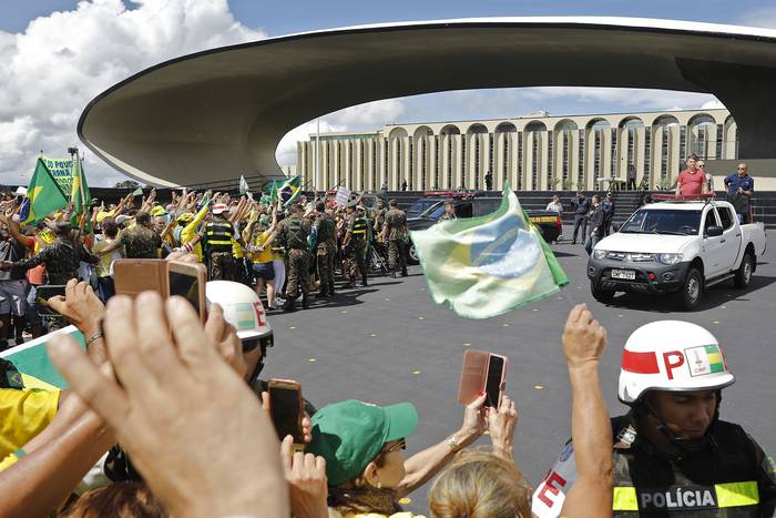 El presidente brasileño Jair Bolsonaro (d) se une a sus partidarios que participan en una caravana para protestar contra las medidas de cuarentena y distanciamiento social, ayer, en Brasilia. · Foto: Sergio Lima, AFP