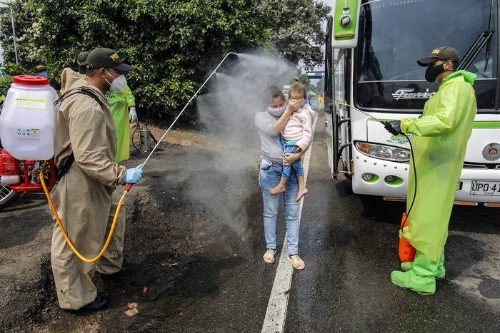 Los miembros de la Policía Nacional desinfectan a los ciudadanos venezolanos en el Puente Internacional Simón Boliviar.
 · Foto: Schneyder Mendoza, AFP
