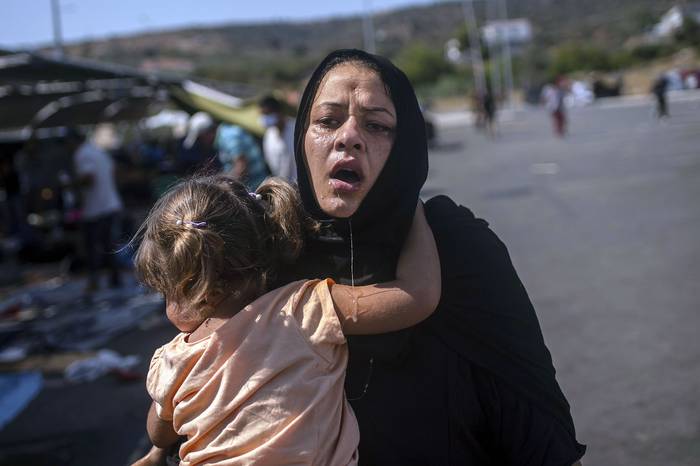 Migrantes mojadas por otro migrante luego de que la policía lanzara gases lacrimógenos durante enfrentamientos, el 12 de setiembre, cerca de la ciudad de Mitilene en la isla griega de Lesbos.
 · Foto: Angelos Tzortzinis, AFP