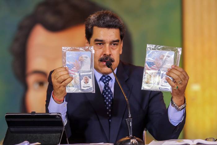 Nicolás Maduro muestra los pasaportes de dos estadounidenses arrestados por las fuerzas de seguridad, el miércoles, en el Palacio Presidencial de Miraflores, en Caracas, Venezuela.
 · Foto: Marcelo García, presidencia de Venezuela.