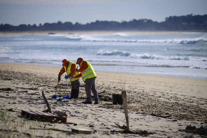 Trabajadores recogen pellets de plástico en la playa de Vilar en Corrubedo, noroeste de España, el 12 de enero de 2024. · Foto: Miguel Riopa / AFP