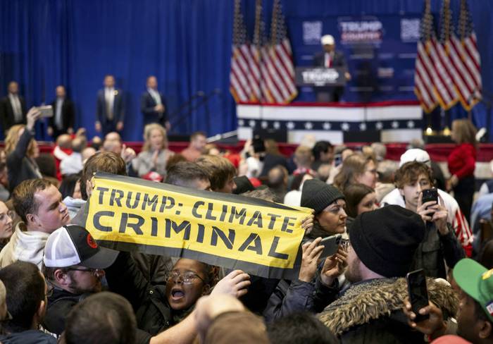 Militantes ambientalistas protestan en un acto electoral del expresidente Donald Trump en Indianola, Iowa. · Foto: Christian Monterrosa, AFP