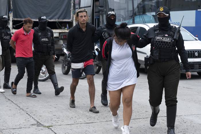 Agentes de la Policía Nacional de Ecuador escoltan a varios presuntos miembros de la banda criminal "Los Lobos" capturados durante un operativo policial luego de que atacaron un puesto policial en Guayaquil, Ecuador, el 14 de enero de 2024. · Foto: Yuri Cortez, AFP