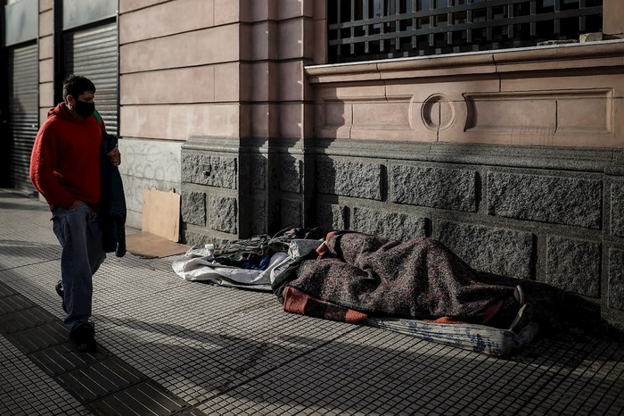 Un hombre camina junto a un grupo de habitantes de calle cerca a la estación ferroviaria de Constitución, Buenos Aires, Argentina. · Foto: Juan Ignacio Roncoroni, EFE 