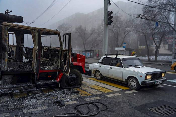 Un coche pasa junto a un vehículo que fue incendiado durante las manifestaciones por la subida de los precios de la energía en Almaty, Kazajistán. El presidente kazajo Kassym-Jomart Tokayev declaró el estado de emergencia hasta el 19 de enero. · Foto: Stringer, Efe