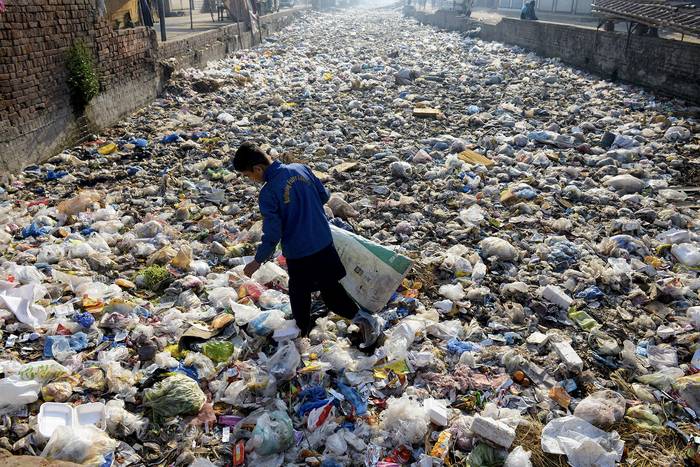 Reciclador en un desagüe de aguas residuales utilizado como vertedero de basura, en un barrio de Lahore, Pakistán. · Foto: Syed Murtaza, AFP