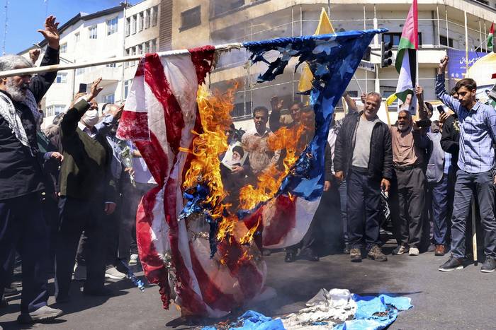 Manifestantes queman una bandera estadounidense y otra israelí durante el funeral de siete miembros del Cuerpo de la Guardia Revolucionaria Islámica muertos en un ataque en Siria,  el 5 de abril en Teherán. · Foto: Atta Kenare, AFP
