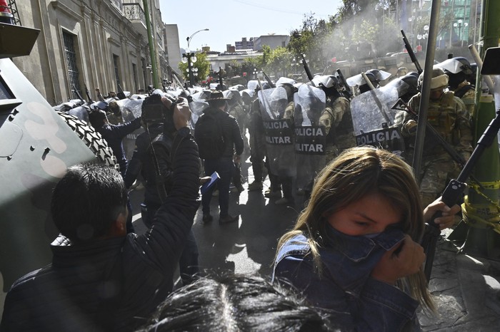 Una mujer se aleja de los gases lacrimógenos disparados por tropas militares frente al Palacio Quemado en la Plaza de Armas de La Paz el 26 de junio de 2024. · Foto: Aizar Raldes, AFP