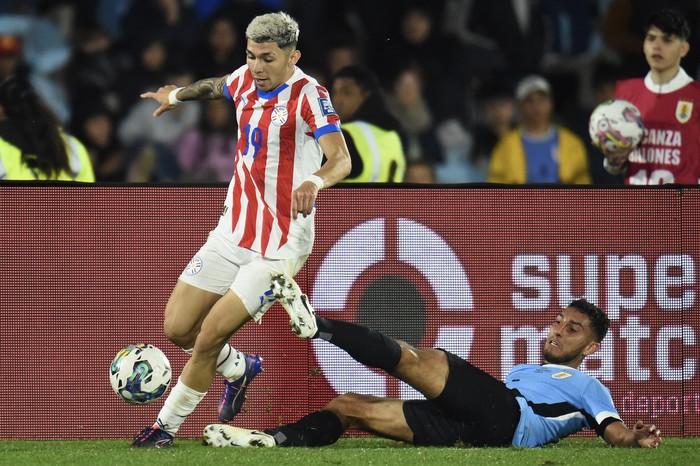 Julio Enciso, de Paraguay, y Sebastián Cáceres, de Uruguay, el 6 de setiembre durante el partido por las eliminatorias, en el estadio Centenario. · Foto: Dante Fernández, AFP