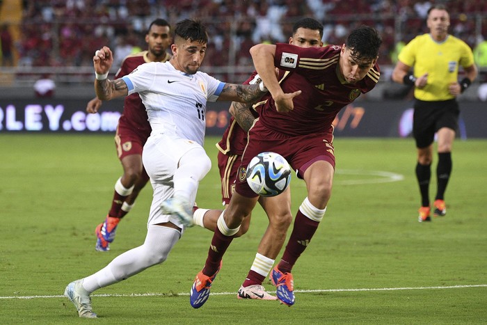 El delantero uruguayo Cristian Olivera y el defensa venezolano Nahuel Ferraresi durante el partido de las Eliminatorias sudamericanas de la Copa Mundial de la FIFA 2026 entre Venezuela y Uruguay en el estadio Monumental de Maturín, Venezuela, el 10 de setiembre de 2024. · Foto: Federico Parra, AFP