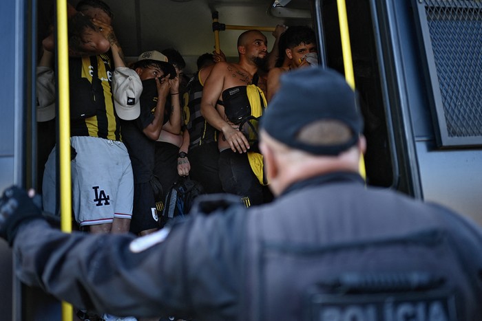 Hinchas de Peñarol son llevados a una comisaría,  el 23 de octubre, luego de ser arrestados durante los enfrentamientos con la policía en una playa de Río de Janeiro. · Foto: Mauro Pimentel, AFP