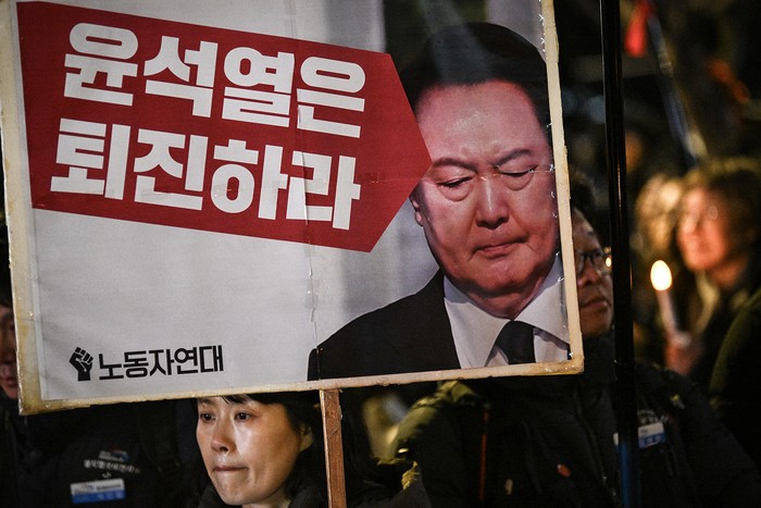 Una mujer sostiene un cartel que dice "Yoon Suk-yeol debería dimitir", el 4 de diciembre, durante una vigilia contra el presidente, en Seúl. · Foto: Philip Fong, AFP