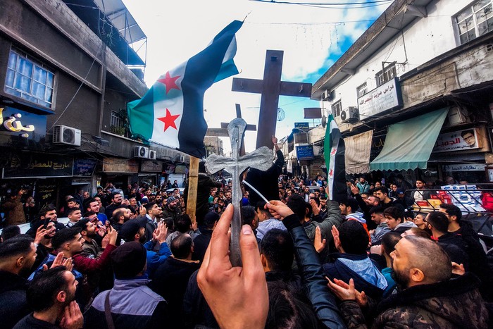 Los cristianos sirios levantan cruces y banderas de la era de la independencia mientras se manifiestan en la zona de Duweilaah en Damasco el 24 de diciembre de 2024. · Foto: Louai Beshara, AFP