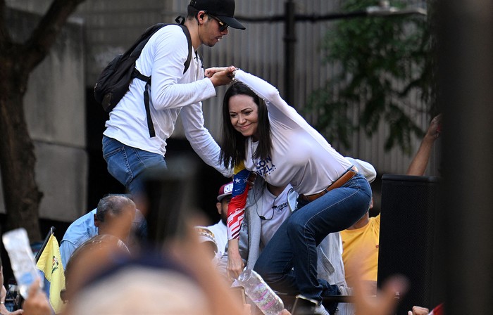 La líder opositora venezolana María Corina Machado es ayudada a subir al escenario durante una protesta convocada por la oposición, este jueves, en Caracas. · Foto: Juan Barreto, AFP