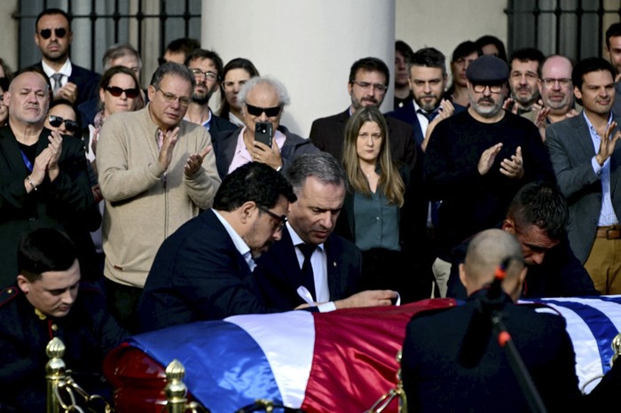 Alejandro Sánchez y el presidente Yamandú Orsi, colocan el pabellón nacional en el féretro de José Mujica. · Foto: Pablo Porciúncula, AFP