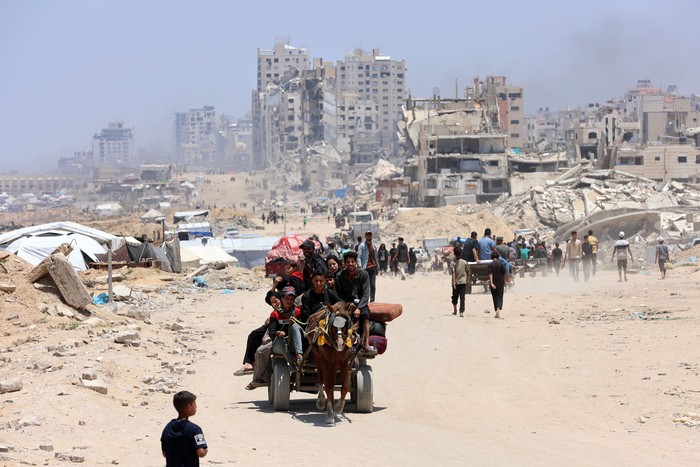 Palestinos transportan sus pertenencias mientras huyen del norte de la Franja de Gaza hacia el sur, por la carretera costera de Al-Rashid, el 25 de mayo de 2025. · Foto: Omar Al-Qattaa, AFP