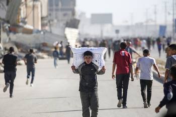 Un joven palestino carga con ayuda alimentaria, el 28 de mayo, después de que un grupo de personas irrumpiera en un almacén del Programa Mundial de Alimentos, en Deir el-Balah, en el centro de la Franja de Gaza. · Foto: Eyad Baba, AFP