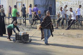 Palestinos reciben paquetes de alimentos distribuidos por el Programa Mundial de Alimentos en la zona de Zawaida de Deir al-Balah, en el centro de la Franja de Gaza, tras la implementación del alto el fuego, el 23 de octubre. · Foto: Hassan Jedi / Anadolu / AFP