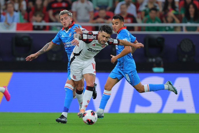 Gonzalo Piovi, del Cruz Azul, Giorgian de Arrascaeta del Flamengo y Carlos Rodríguez del Cruz Azul durante el Derbi de las Américas de la FIFA entre Cruz Azul y Flamengo en el Estadio Ahmad Bin Ali en Doha el 10 de diciembre de 2025. 
Foto:  Karim Jaafar/AFP