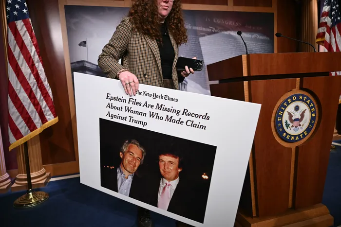 Un personal del congreso sostiene un cartel con una foto de Donald Trump y Jeffrey Epstein, el 26 de febrero, en el Capitolio de los Estados Unidos, en Washington. · Foto: Brendan Smialowski, AFP