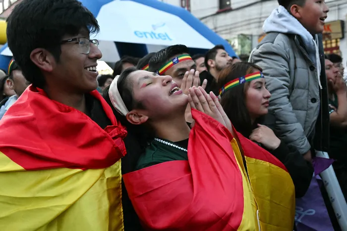 Aficionados bolivianos reaccionan mientras ven a su selección enfrentarse a Surinam en el partido de semifinales de la repesca de las eliminatorias para la Copa Mundial de la FIFA 2026 en una pantalla gigante en La Paz, el 26 de marzo. · Foto: Aizar Raldes