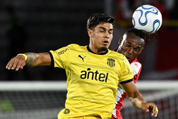 Matías Arezo, de Peñarol, y Víctor Moreno, de Santa Fe, por la fase de grupos de la Copa Libertadores, el 9 de abril de 2026, en el estadio El Campín, Bogotá. Foto: Luís Acosta / AFP