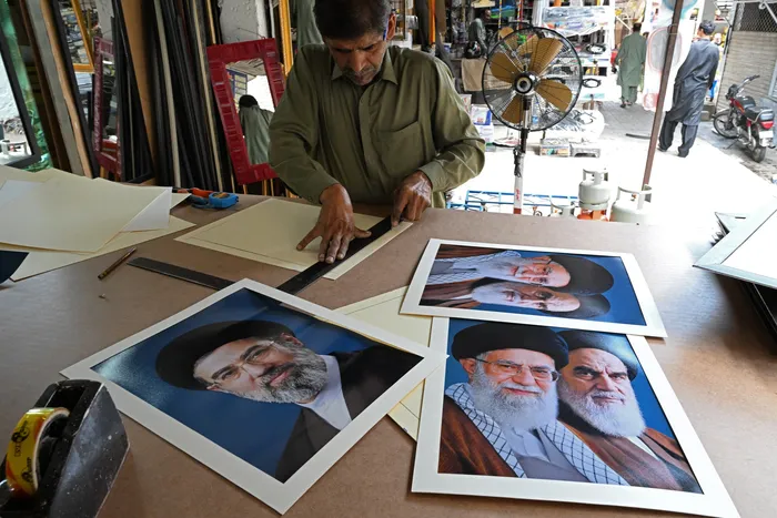 Un artesano prepara retratos del líder supremo de Irán, Mojtaba Jamenei (izq), el miércoles 29, en un mercado de Islamabad. · Foto: Aamir Qureshi, AFP