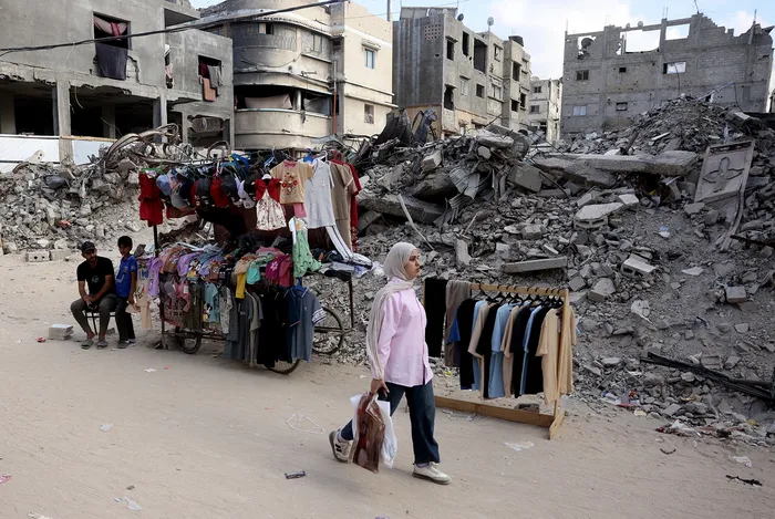 Puesto de ropa instalado cerca de los escombros de los edificios destruidos en los ataques militares israelíes, el 26 de mayo, al sur de la Franja de Gaza. · Foto: Bashar Taleb, AFP