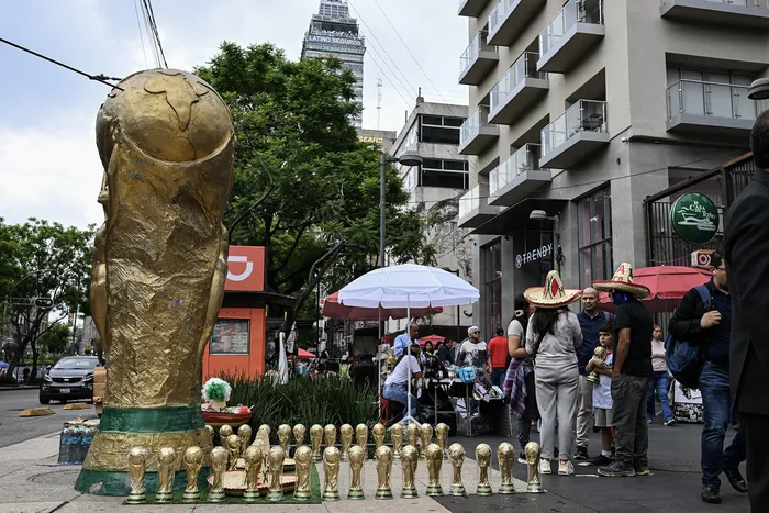 Vendedores ambulantes exhiben recuerdos con forma de trofeo del Mundial de la FIFA en una calle de Ciudad de México. · Foto: Yuri Cortez / AFP