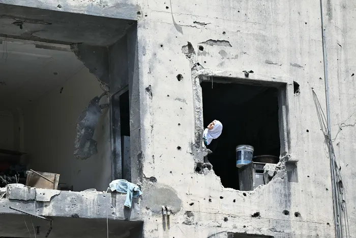 Una mujer en un edificio en ruinas en el sur de Líbano, el 23 de junio. · Foto: Joseph Eid, AFP
