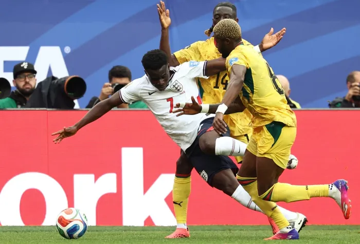 El delantero inglés Bukayo Saka disputa el balón con los ghaneses Kwasi Sibo y Gideon Mensahde en el partido por el grupo L del Mundial 2026, en el Boston Stadium de Foxborough, el 23 de junio. · Foto: Franck Fife,  AFP