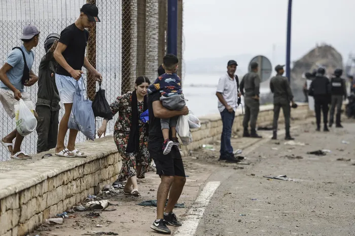 Una familia durante enfrentamientos entre las fuerzas de seguridad marroquíes y los migrantes que intentaban cruzar al enclave español de Ceuta. · Foto: Abdel Majid Bziquat, AFP