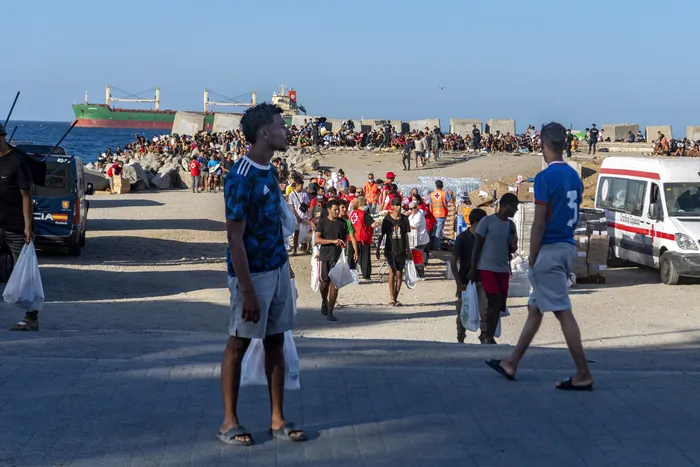 Voluntarios de la Cruz Roja reparten alimentos a migrantes que permanecen viviendo en la
calle, en la playa del Trampolín de Ceuta, el 22 de agosto. · Foto: Antonio Sempere, AFP