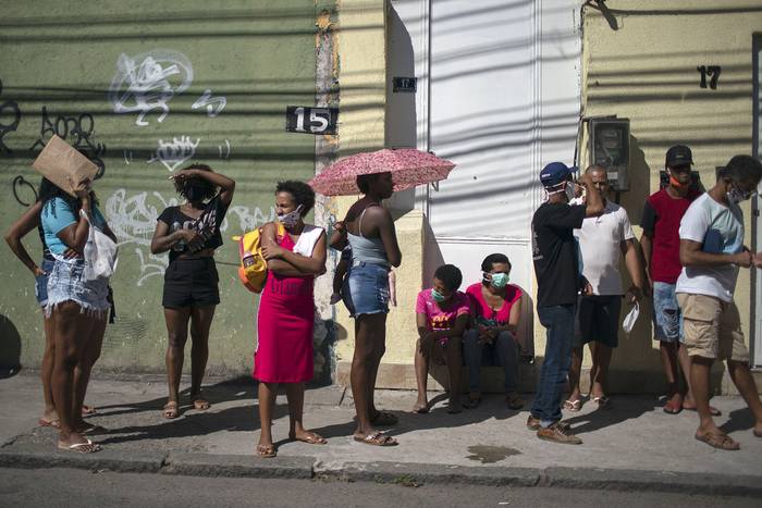 Personas esperan fuera del Banco estatal Caixa Economica, para recibir ayuda económica, en Río de Janeiro, Brasil (archivo, abril de 2020). · Foto: Mauro Pimentel, AFP