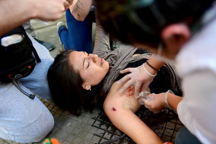 Una mujer recibe asistencia después de recibir un disparo con una bala de goma durante los enfrentamientos con la policía, durante las protestas contra un aumento en los precios de los boletos del metro, en Santiago (archivo, octubre de 2019). · Foto: Martín Bernetti, AFP