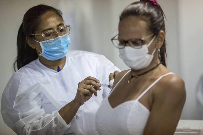 Una mujer recibe una dosis de una vacuna contra el Covid-19, en una carpa en la playa de Copacabana, el 31 de diciembre, en Río de Janeiro. · Foto: Daniel Ramalho, AFP