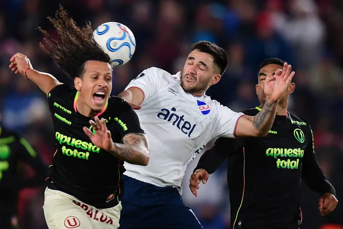 Williams Riveros y Anderson Santamaría, de Universitario, con Maximiliano Gómez, de Nacional, el 20 de mayo, por la fase de grupos de la Copa Libertadores, en el Gran Parque Central. · Foto: Dante Fernández, AFP