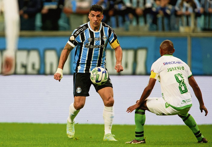 Luis Suárez, de Gremio, y Juninho, del América Mineiro, durante el partido por el campeonato de la Serie A, el 22 de junio, en el estadio Arena do Gremio de Porto Alegre, Brasil. · Foto: Silvio Ávila / AFP