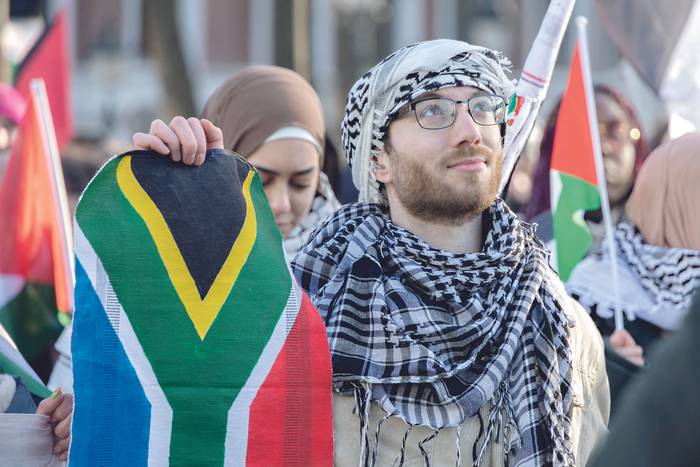 Manifestantes con banderas de Sudáfrica y Palestina frente a la Corte Internacional de Justicia, el 26 de enero. · Foto: Nikos Oikonomou / Anadolu / AFP