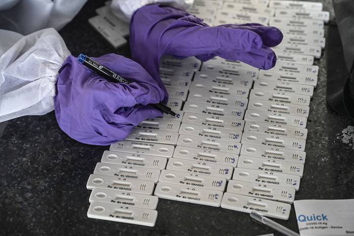 Trabajadores de la salud preparan kits de prueba rápida de antígenos (RAT) para pasajeros que llegan a la ciudad en una terminal ferroviaria, el 29 de marzo, en Bombay, India.
 · Foto: Indranil Mukherjee, AFP
