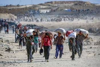 Palestinos regresan de un punto de distribución de alimentos, el 5 de octubre, cerca del corredor de Netsarim en el centro de la Franja de Gaza. · Foto: Eyad Baba, AFP