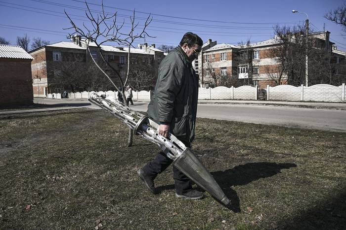 Un habitante de Kharkiv, carga un fragmento de un cohete de racimo luego de un ataque ruso. · Foto: Aris Messinis, AFP