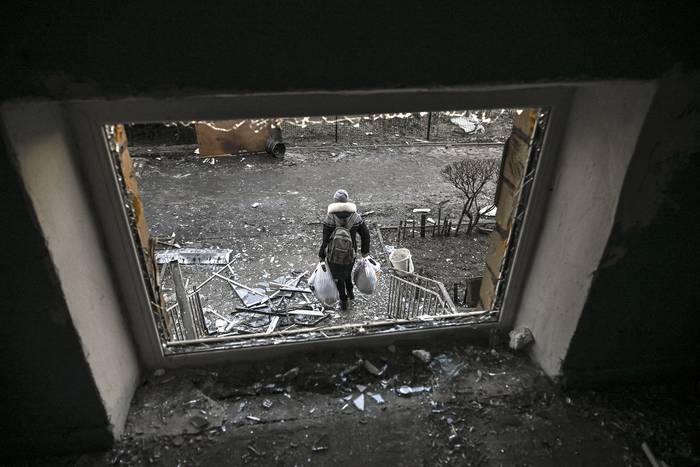 Una mujer sale de un edificio destruido tras un bombardeo ruso, en un suburbio residencial al norte de Kiev. · Foto: Aris Messinis, AFP