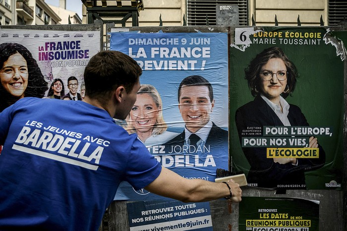 Un voluntario del partido de extrema derecha Encuentro Nacional de Francia en pegatina de campaña del presidente del partido y candidato a las elecciones al Parlamento Europeo, Jordan Bardella, en Lyon el 6 de junio de 2024 · Foto: Jeff Pachoud, AFP
