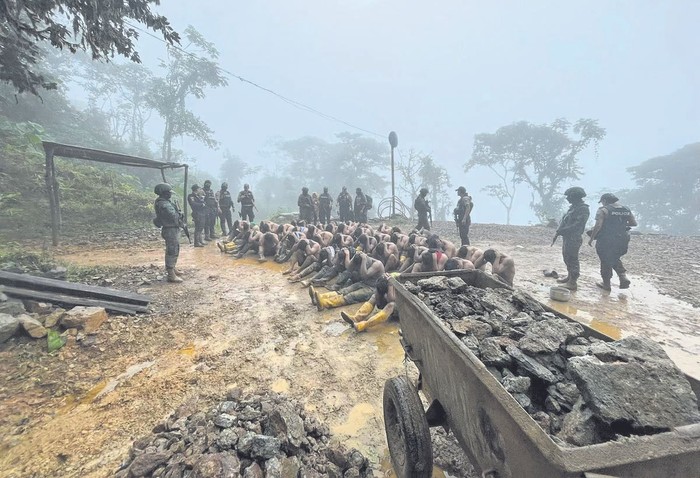 Soldados y policías custodian a presuntos miembros de Los lobos durante una operación conjunta  en una mina en el sector de Santa Martha de Camilo Ponce Enriquez, Ecuador, el 3 de julio. En la operación rescataron a 49 personas que los narcotraficantes tenían secuestradas. · Foto: Fuerzas Armadas de Ecuador, AFP