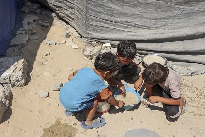 Niños palestinos comparten un plato de sopa de lentejas, en la ciudad de Gaza. · Foto: Omar Al-Qattaa, AFP
