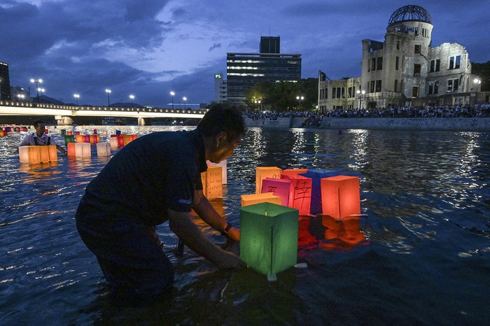 Voluntarios colocan linternas de papel en el río Motoyasu frente a la Cúpula de la Bomba Atómica al conmemorar el 80º aniversario del primer ataque con bomba atómica, ocurrido en la ciudad de Hiroshima. · Foto: Richard A. Brooks, AFP